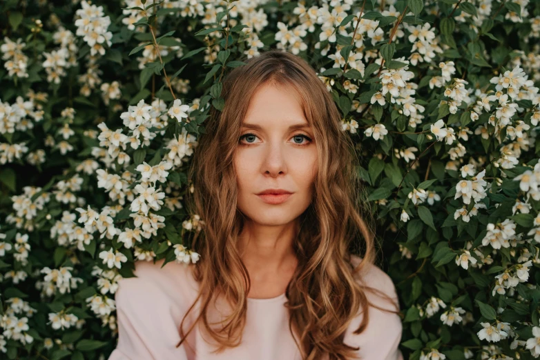 a woman standing in front of a bush of white flowers, a picture, by Julia Pishtar, pexels contest winner, no makeup wavy hair, elizabeth olsen, perfect face ), alexey gurylev