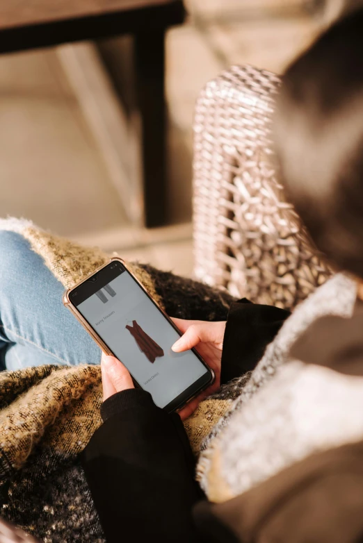 a woman sitting on a couch holding a cell phone, by Niko Henrichon, trending on pexels, happening, sitting on a store shelf, sustainable materials, brown, seasonal