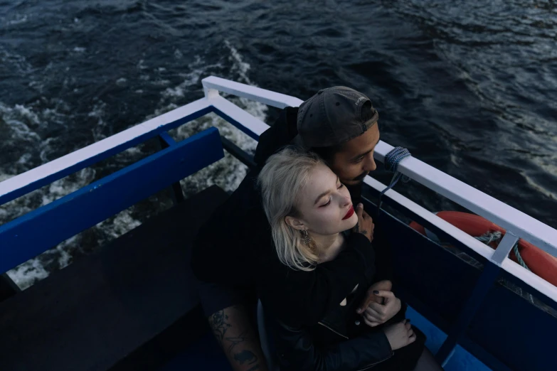 a man and a woman sitting on a boat, inspired by Nan Goldin, pexels contest winner, happening, blonde, black, indigo, embracing