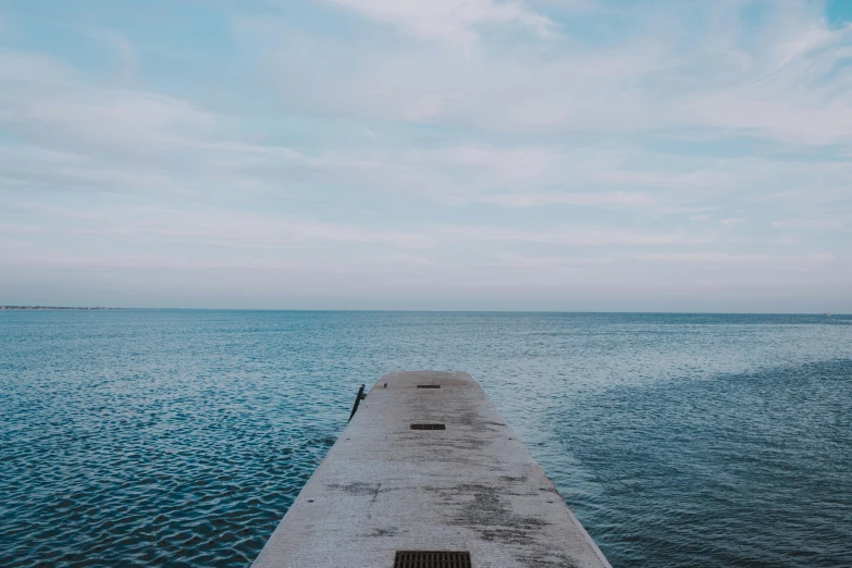 a concrete pier in the middle of a body of water, unsplash, background image, black sea, instagram post, conor walton