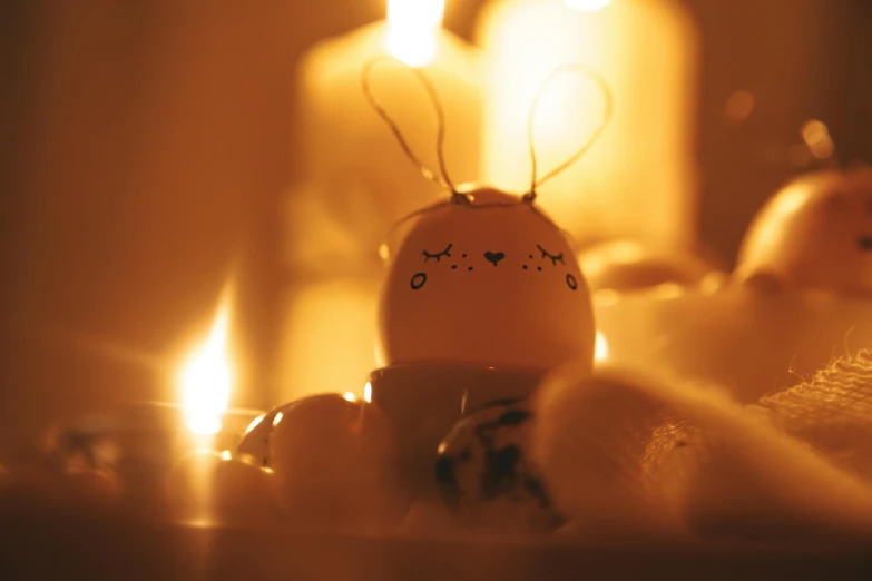 a couple of eggs sitting on top of a table, on a candle holder, at night, bunny head, cosy vibes