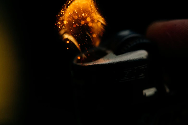 a person holding a lighter in their hand, a macro photograph, pexels contest winner, process art, blackening effect, shot on hasselblad, low quality footage, glimmering