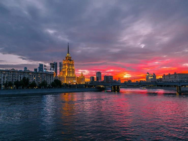 a large body of water with buildings in the background, an album cover, by Alexander Runciman, pexels contest winner, socialist realism, sunset panorama, in moscow centre, building along a river, red river