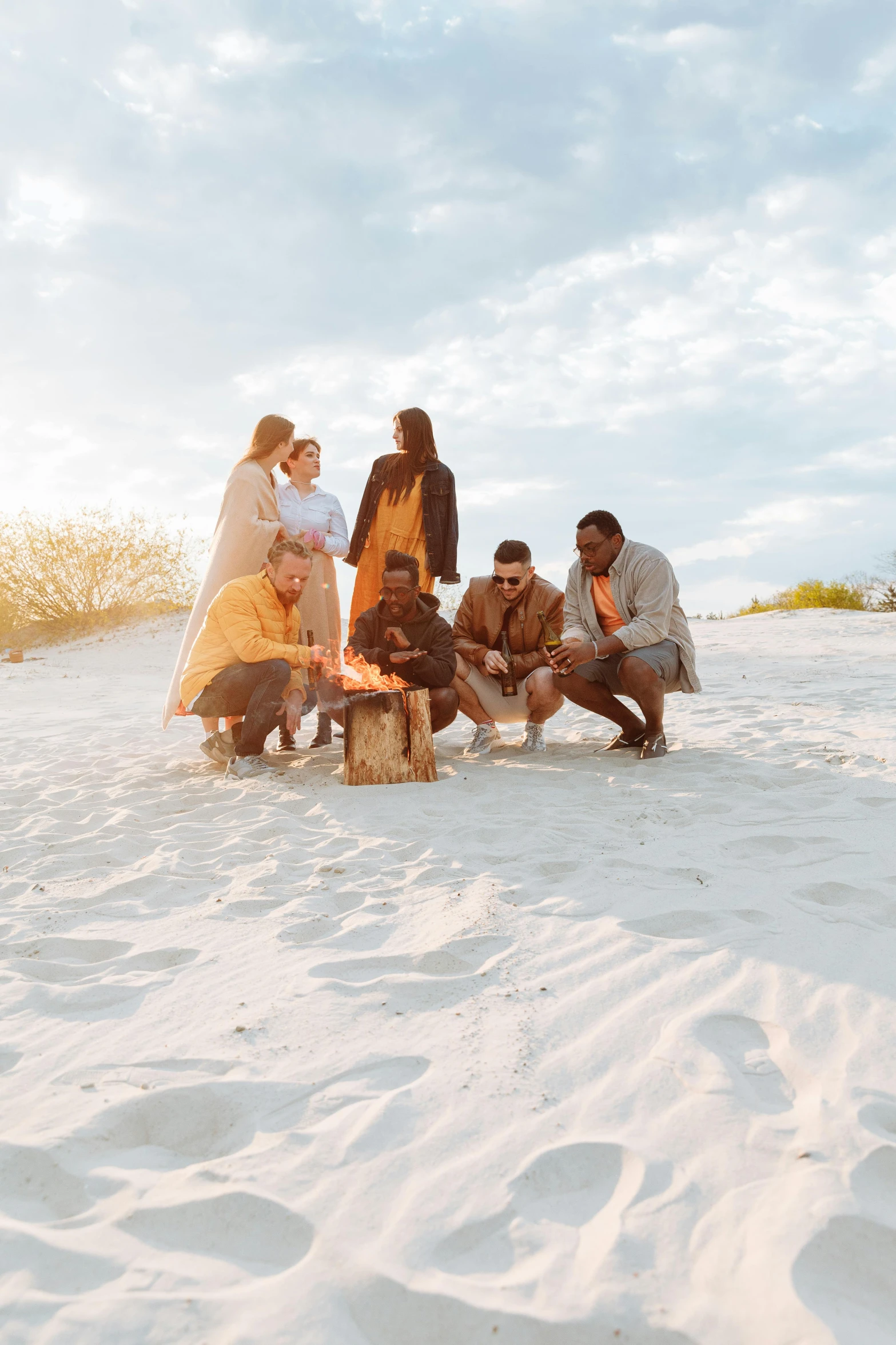 a group of people sitting on top of a sandy beach, by Jessie Algie, pexels contest winner, small fire, white sand, aboriginal, boho chic