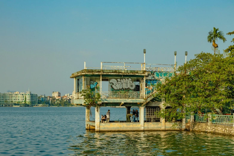 a building sitting on top of a body of water, an album cover, phuoc quan, afternoon hangout, f/3.5, high-quality photo