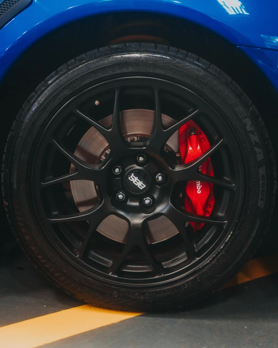 a blue sports car parked in a parking lot, by Adam Marczyński, pexels contest winner, black wheel rims, red on black, gravels around, side view close up of a gaunt