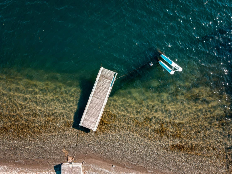 a couple of boats sitting on top of a body of water, a picture, by Elsa Bleda, pexels contest winner, minimalism, boat dock, looking down from above, the lost beach, picton blue
