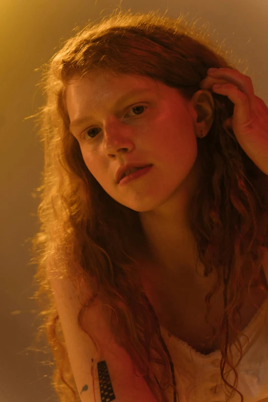 a woman brushing her hair in front of a mirror, inspired by Nan Goldin, renaissance, ginger wavy hair, barely lit warm violet red light, young teen, movie still of a tired