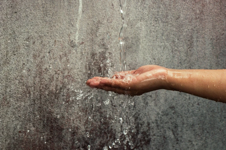 a person's hand is sprinkled with water, inspired by Lucio Fontana, unsplash, concrete wall, commercial washroom hand dryer, natural realistic render, “hyper realistic