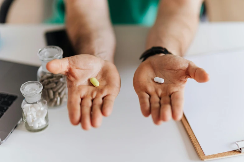 a person sitting at a table with pills in their hands, by Daniel Lieske, pexels, a person standing in front of a, holding an epée, a muscular, image split in half