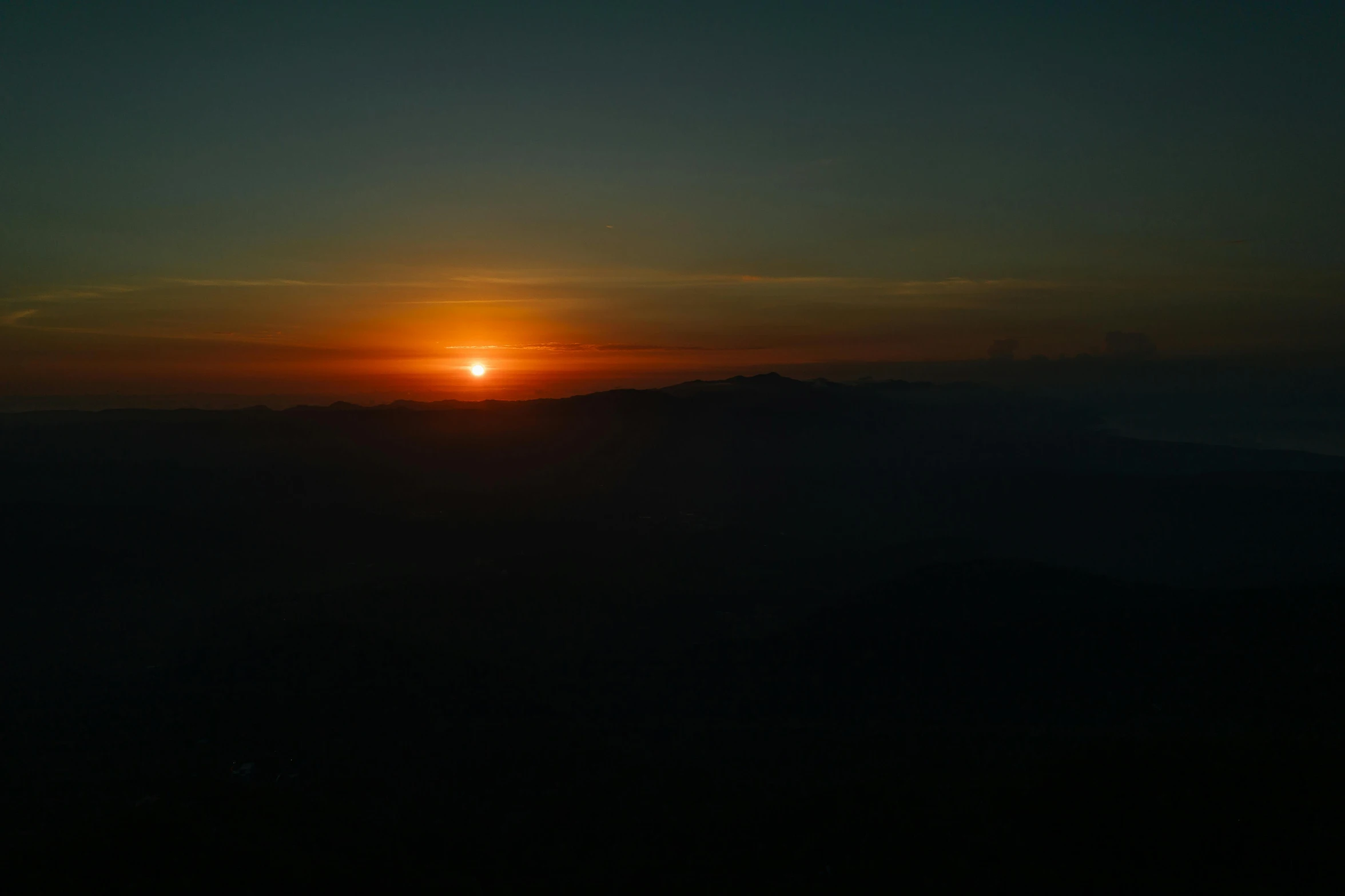 the sun is setting over the mountains in the distance, by Sebastian Spreng, pexels contest winner, sumatraism, hot sun from above, sparse mountains on the horizon, dark, view from the top