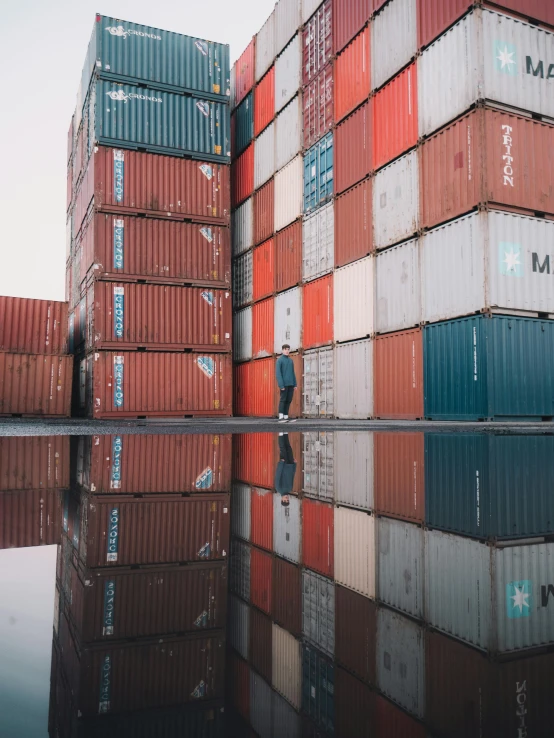 a man standing in front of a large stack of shipping containers, pexels contest winner, very reflective, gif, programming, instagram picture