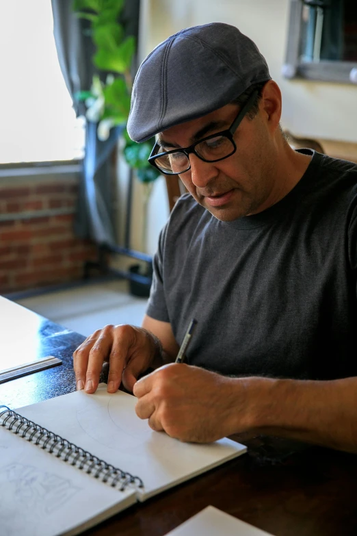 a man sitting at a table writing on a notebook, by Joe Stefanelli, process art, asher duran, joe rogan, high quality picture, pixar portrait