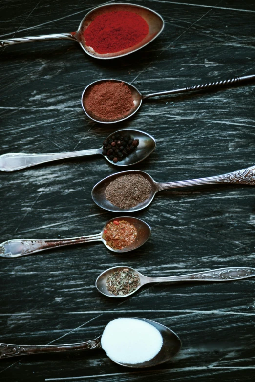 a group of spoons sitting on top of a table, spices, meteorites, grey, deep colour