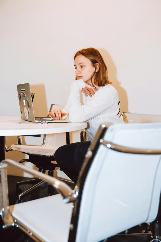 a woman sitting at a table with a laptop, an all white human, 2019 trending photo, looking away from camera, people sitting at tables