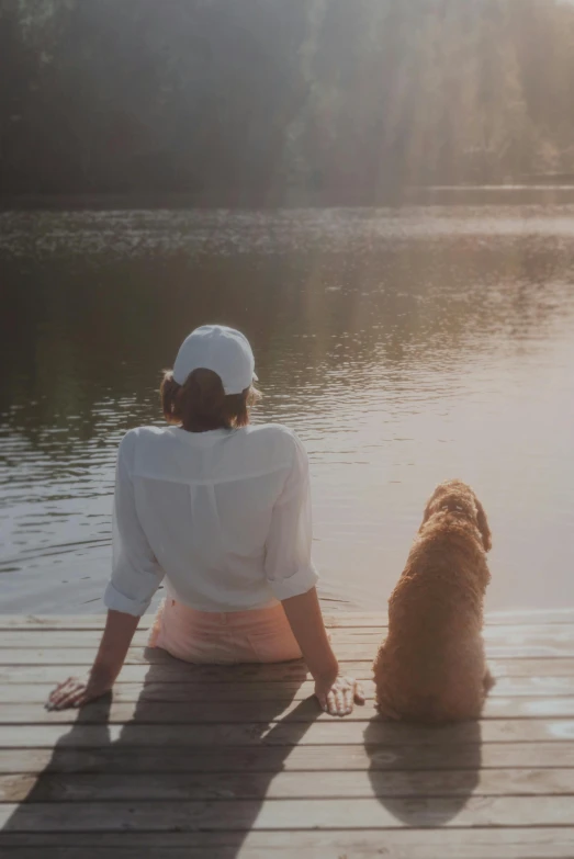 a woman sitting on a dock next to a dog, pexels contest winner, renaissance, soft golden light, lake house, paul barson, best friends