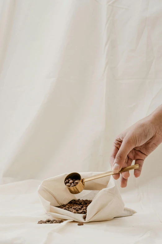 a person holding chopsticks over a bowl of food, an album cover, by Julia Pishtar, pexels contest winner, minimalism, coffee beans, white and gold robes, gif, spoon