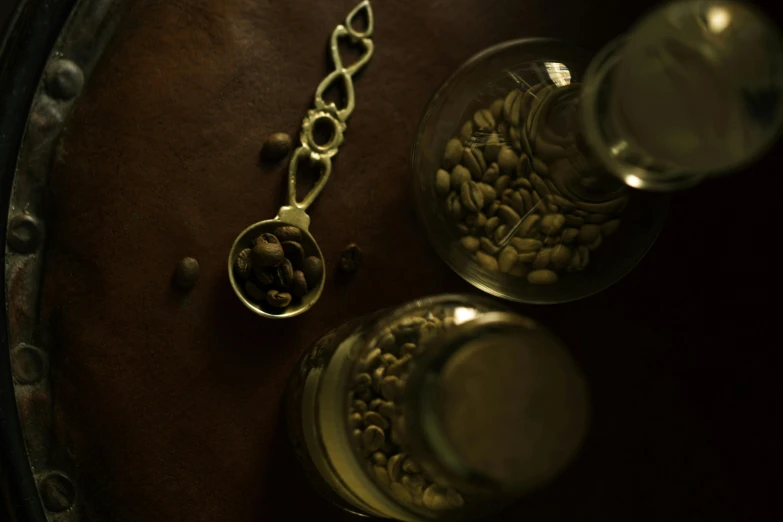 a clock sitting on top of a wooden table, a still life, inspired by Ceferí Olivé, trending on unsplash, renaissance, coffee beans, absinthe, silver small small small glasses, taken with sony alpha 9