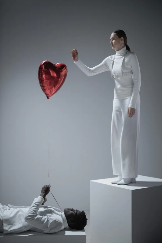 a woman holding a red balloon in the shape of a heart, a surrealist sculpture, inspired by Marina Abramović, pexels contest winner, magic realism, wearing futuristic white suit, wearing human air force jumpsuit, digital sculpture, weightlessness