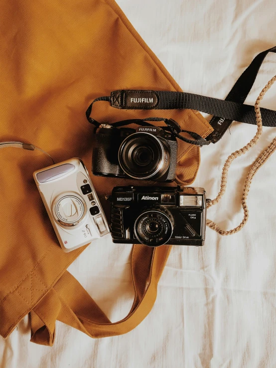 a couple of cameras sitting on top of a bed, by Andrée Ruellan, warm color clothes, 📷 mungojerrie and rumpleteazer, camera close up, trending on vsco