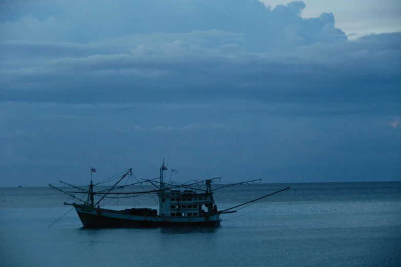 a boat in a body of water under a cloudy sky, by Elsa Bleda, unsplash contest winner, sumatraism, fishing, blue gray, dimly lit, slide show