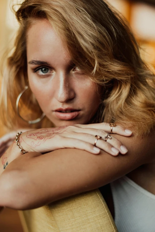 a beautiful young woman sitting on top of a couch, a tattoo, by Mathias Kollros, trending on pexels, renaissance, gold rings, square, jewelry photography, zoomed in