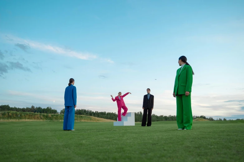 a group of people standing on top of a lush green field, by Marina Abramović, wearing a colorful men's suit, golf course, eva elfie, blue and pink shift