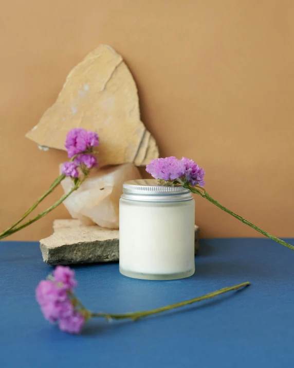 a candle sitting on top of a blue table, product display photograph, translucent stone white skin, jar on a shelf, full product shot