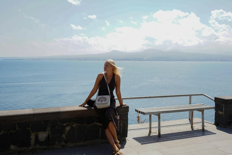 a woman sitting on a ledge overlooking the ocean, a picture, happening, liz truss, sitting on bench, avatar image, skye meaker