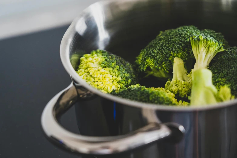 a pot filled with broccoli sitting on top of a stove, by Julia Pishtar, pexels, stainless steel, organic detail, salad, glossy surface