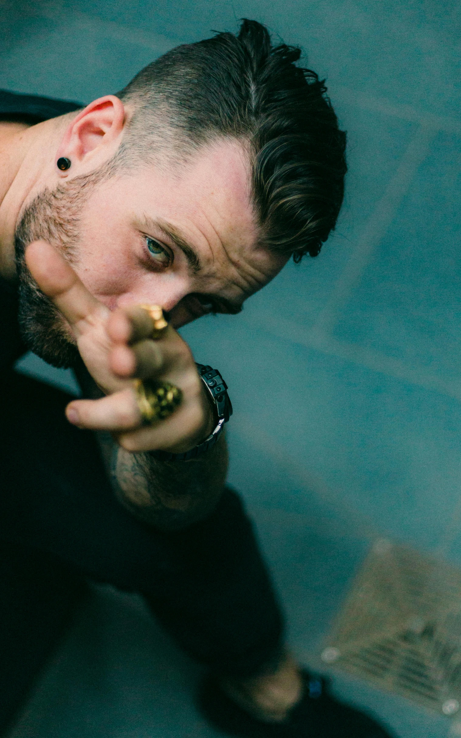 a man pointing a gun at the camera, a tattoo, by Brian 'Chippy' Dugan, unsplash, glass and gold pipes, vocalist, portrait of adam jensen, crouching