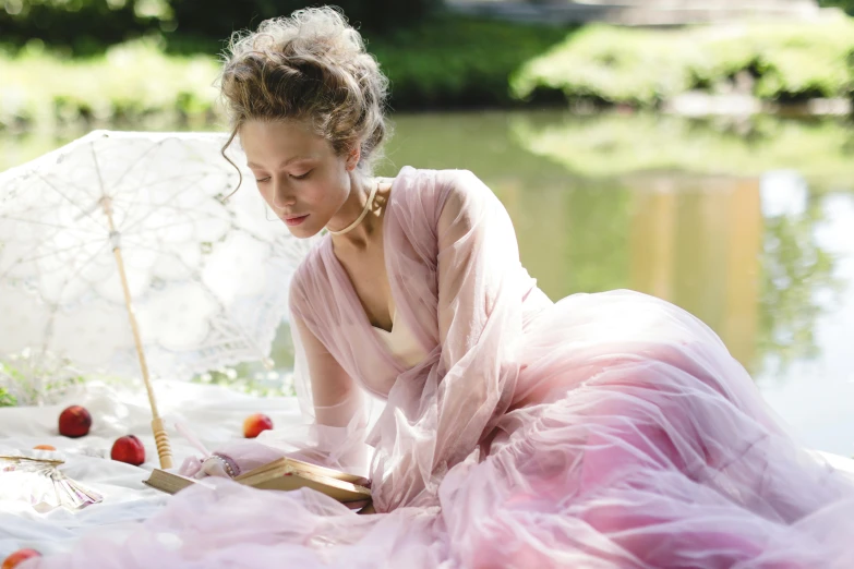 a woman in a pink dress holding an umbrella, inspired by Cassandra Austen, pexels contest winner, with one vintage book on a table, wearing organza gown, al fresco, nathalie emmanuel