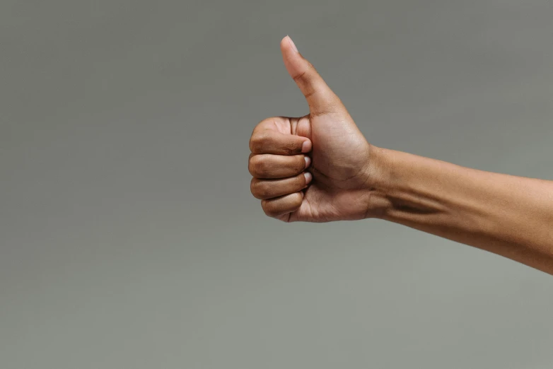 a close up of a person's hand giving a thumbs up, trending on pexels, hurufiyya, on grey background, curvy build, background image