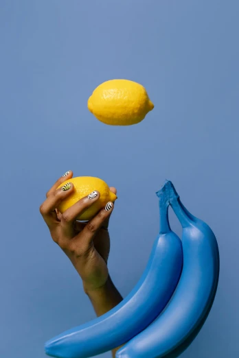 a person holding two bananas and a lemon, by Doug Ohlson, blue mood, painted nails, malika favre, f / 2 0