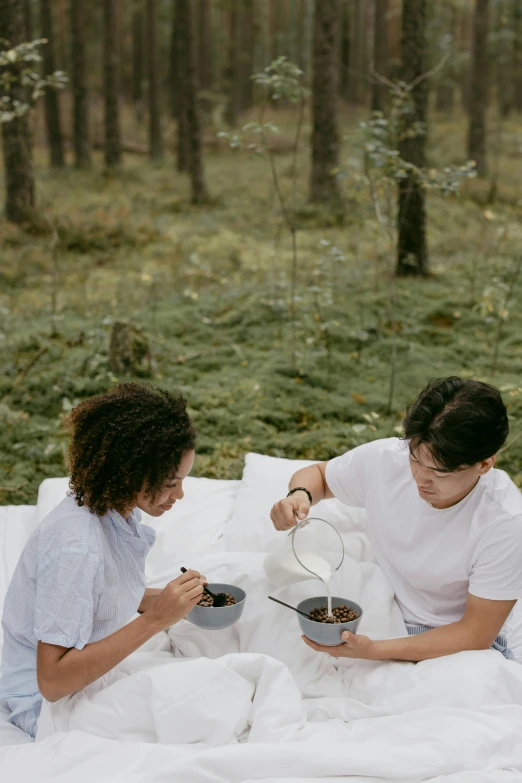 a couple of people sitting on top of a blanket, forest picnic, two cups of coffee, blending, botanicals