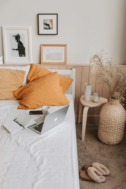 a bed with a laptop sitting on top of it, by Andries Stock, trending on pexels, some sandy yellow pillows, white and orange, rustic, angle view