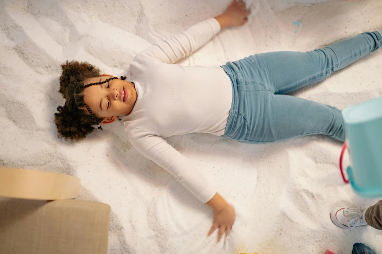 a little girl laying on top of a pile of sand, pexels contest winner, white shirt and jeans, in the bedroom at a sleepover, zero gravity, african american young woman