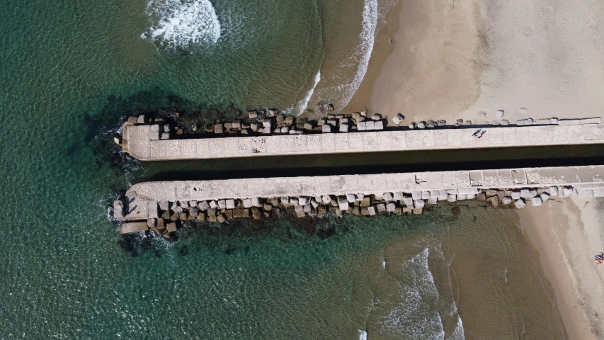 a bridge over a body of water next to a beach, pexels contest winner, conceptual art, top - down perspective, concrete pillars, south african coast, submarine camera imagery