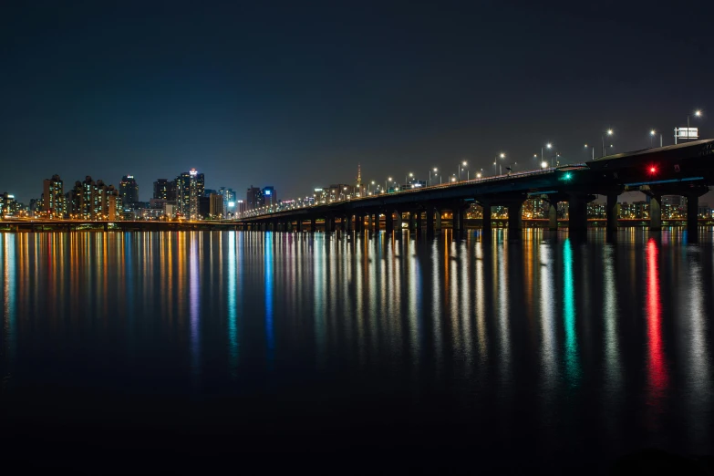 a bridge over a body of water at night, by Jang Seung-eop, pexels contest winner, urban skyline, various colors, clear reflection, korean