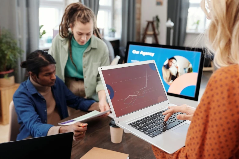 a group of people sitting around a table with laptops, by Carey Morris, trending on pexels, close up to the screen, teaching, full colour, alana fletcher