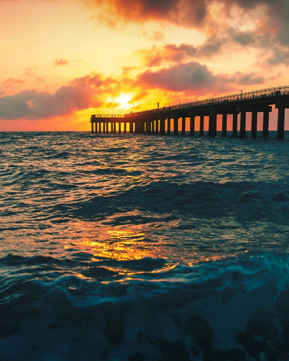 a sunset over the ocean with a pier in the background, pexels contest winner, renaissance, lgbtq, ocean swells, caught on camera, photo of a beautiful