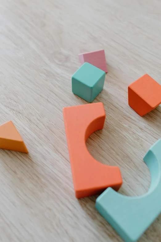 a close up of a wooden object on a table, a jigsaw puzzle, trending on pexels, hypermodernism, solid coloured shapes, building blocks, toys, curving geometric arches