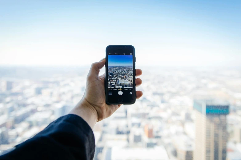 a person taking a picture of a city with a cell phone, pexels contest winner, towering high up over your view, rectangle, iphone, 3 6 0 picture