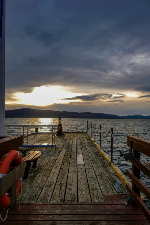 a couple of benches sitting on top of a wooden pier, skye meaker, sunset with cloudy skies, on the deck of a ship, today\'s featured photograph 4k