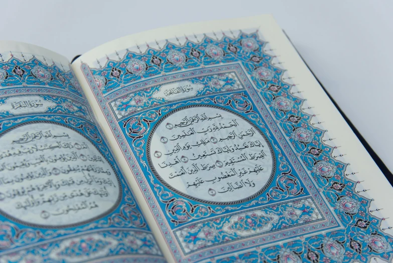 a close up of an open book with arabic writing, by Sheikh Hamdullah, pexels, hurufiyya, sky blue, glossy intricate design, a high angle shot, with ornamental edges