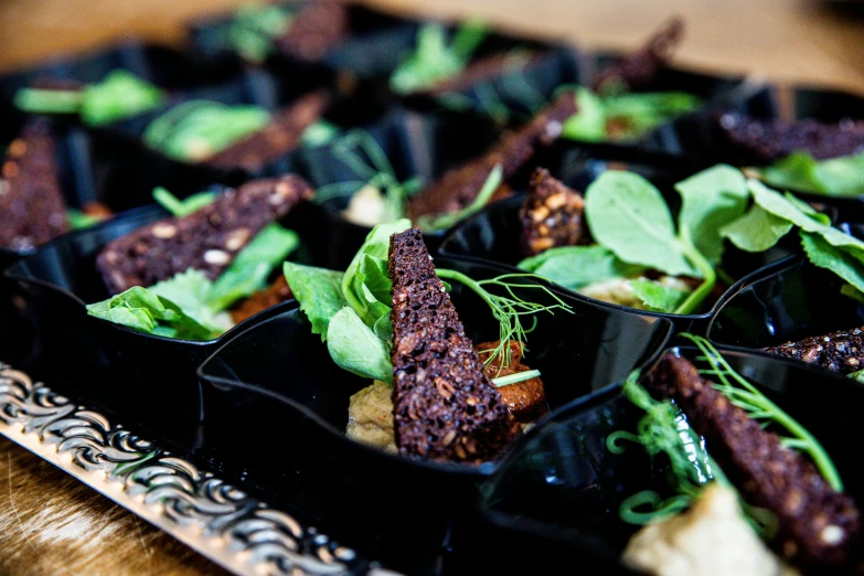 a close up of a tray of food on a table, by Joe Bowler, black tendrils, herbs, very crispy, muspelheim