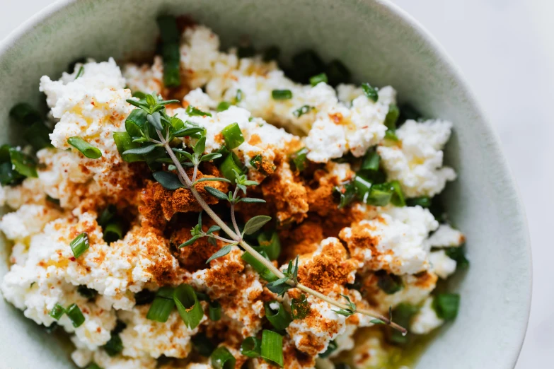 a close up of a bowl of food on a table, by Carey Morris, trending on pexels, gypsophila, spicy, mozzarella, humus