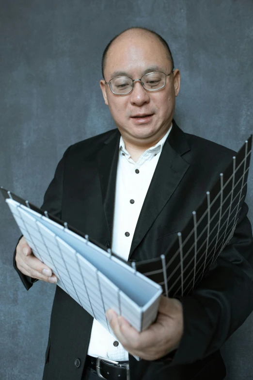 a man in a suit holding a sheet of music, inspired by Fei Danxu, grid and web, press shot, engineer, dzung phung dinh