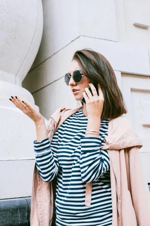 a woman in a striped dress talking on a cell phone, trending on pexels, wearing a cape, neat nails, technological sunglasses, brunette woman