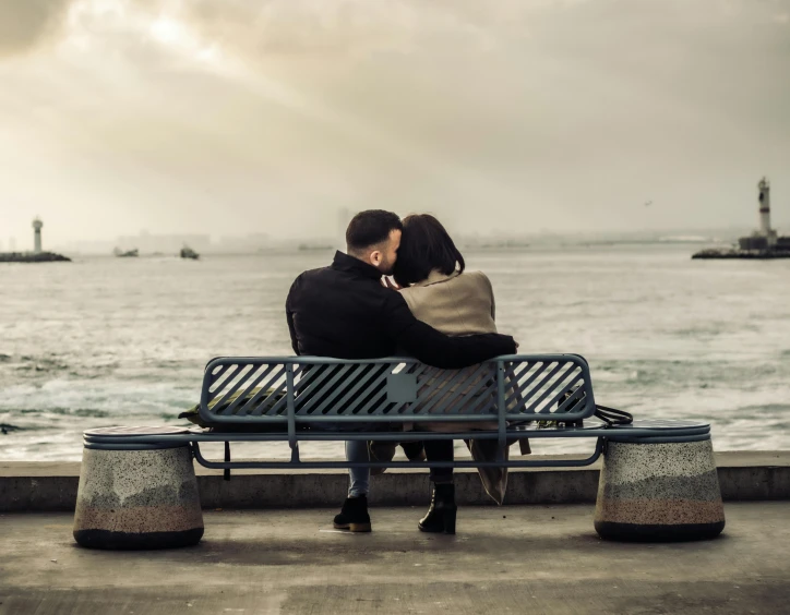 a couple is sitting on a bench by the water, pexels contest winner, holding each other, post-processed, january 20th, seaside